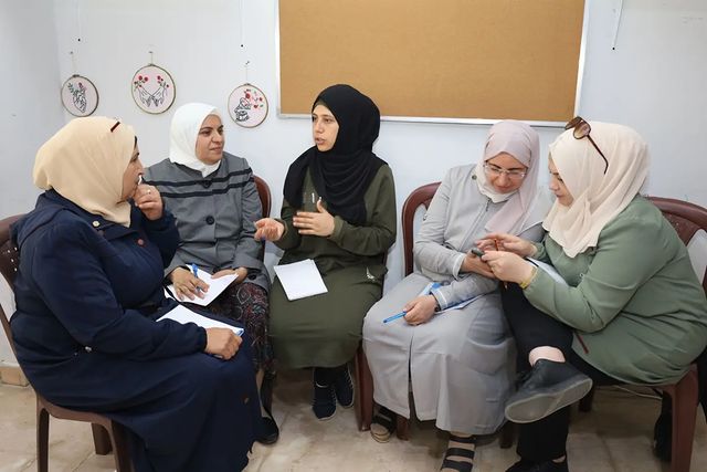 a group of Hijabi women sit around speaking to one another