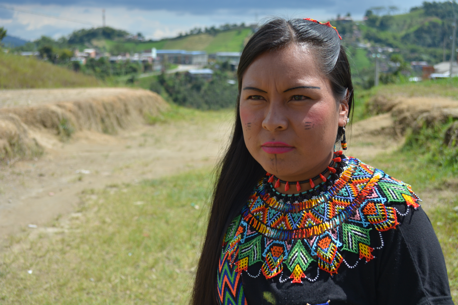 a young Indigenous Colombian woman stands in a field