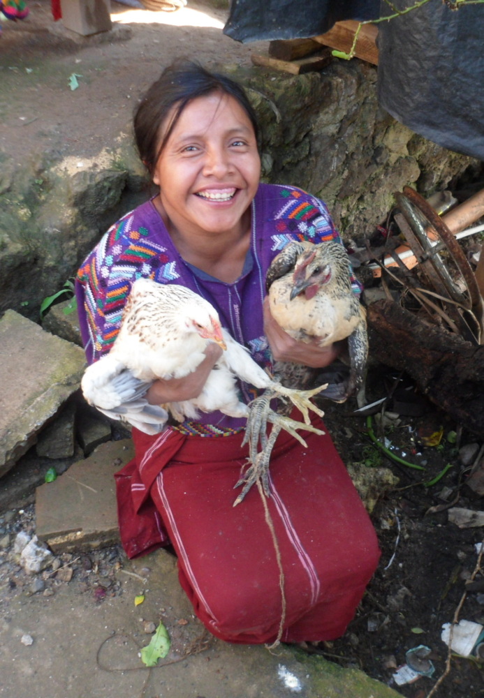 a young Indigenous woman in Guatemala holds two chickens