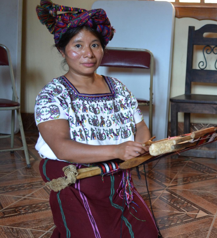 a young Indigenous Guatemalan woman sits weaving