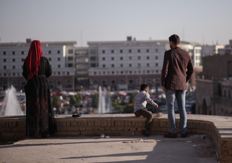a woman, man, and child lookout over a town square