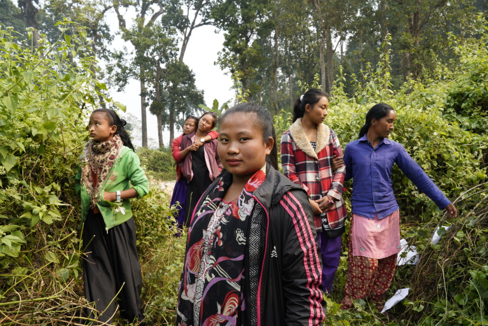 Santoshi, from Nepal, stands in the forest surounded by other young women