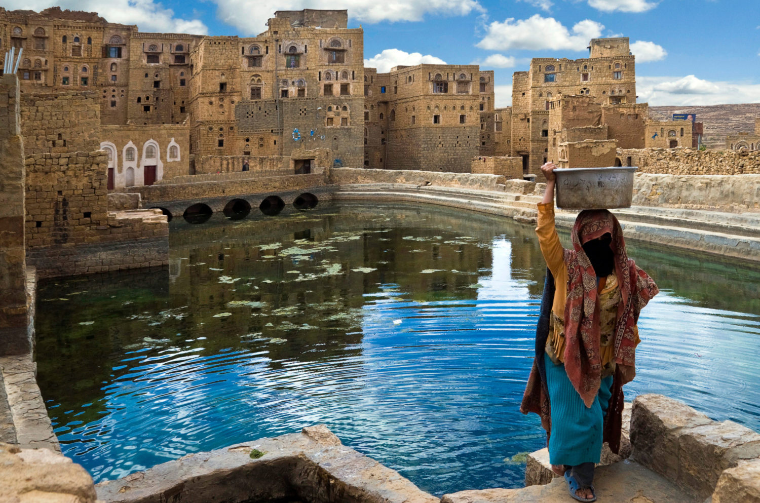 a woman gathers water in Yemen city