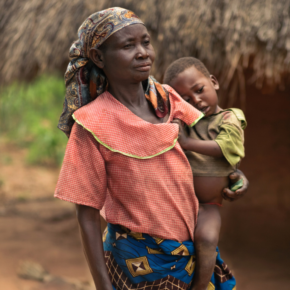 a Congolese mother stands holding her child in her arms