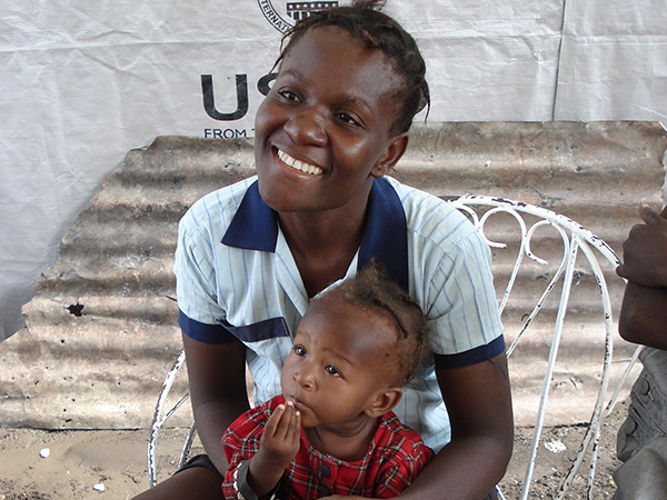 a Haitian woman sits in a chair holding her child