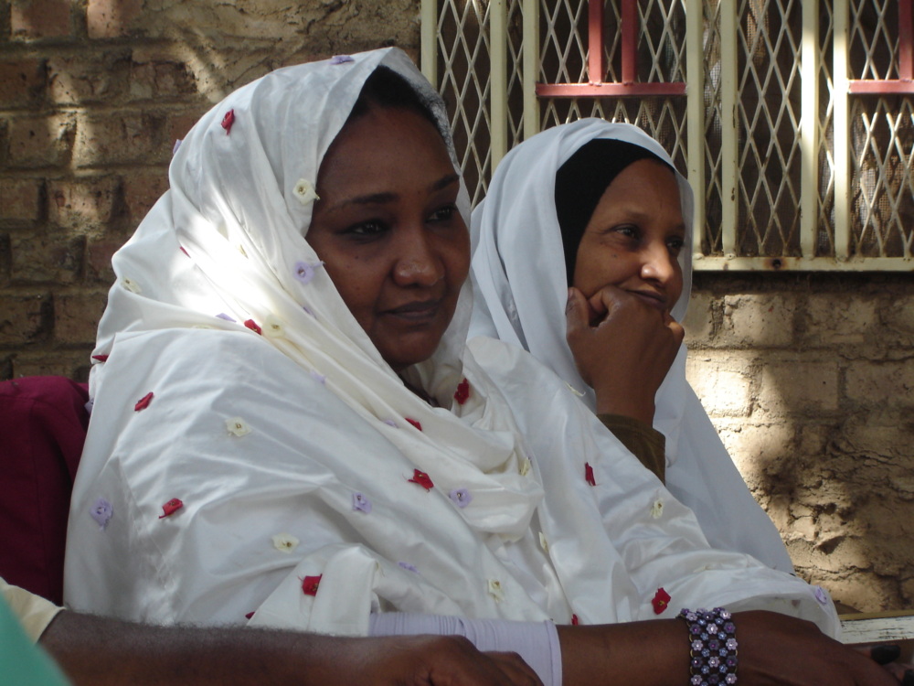 Fatima Ahmed sits with another women listening to a someone speak