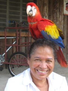 Rose Cunninham Kain smiles as a colorful parrot rests on her head.