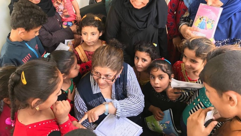 Yanar Mohammed sits and talks with a group of young Iraqi children at a local shelter.